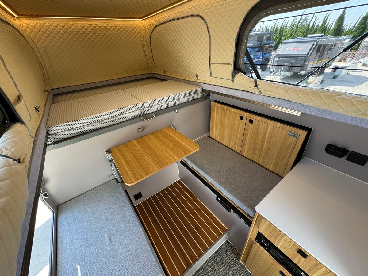 Innenraum des WildPORT FLAT ROAD Pickup Campers mit Sitzgruppe und Bett